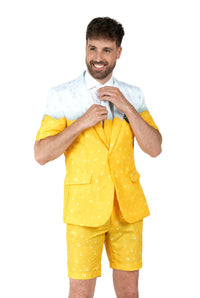 A man smiles while adjusting his collar, wearing Suitmeisters Premium Beer Yellow suit jacket with a matching yellow shirt and shorts in a playful pattern, standing against a white background.