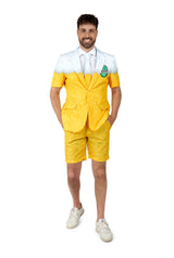 A man wears the Suitmeister Premium Beer Yellow short-sleeve suit with matching shorts, a white shirt, and white sneakers, smiling with his hands in his pockets against a plain white background.