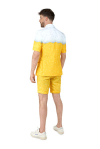 A man stands with his back turned, wearing the Suitmeister Premium Beer Yellow novelty suit—featuring a white foam top, yellow bubbles, matching shorts, and white sneakers—against a plain white background.