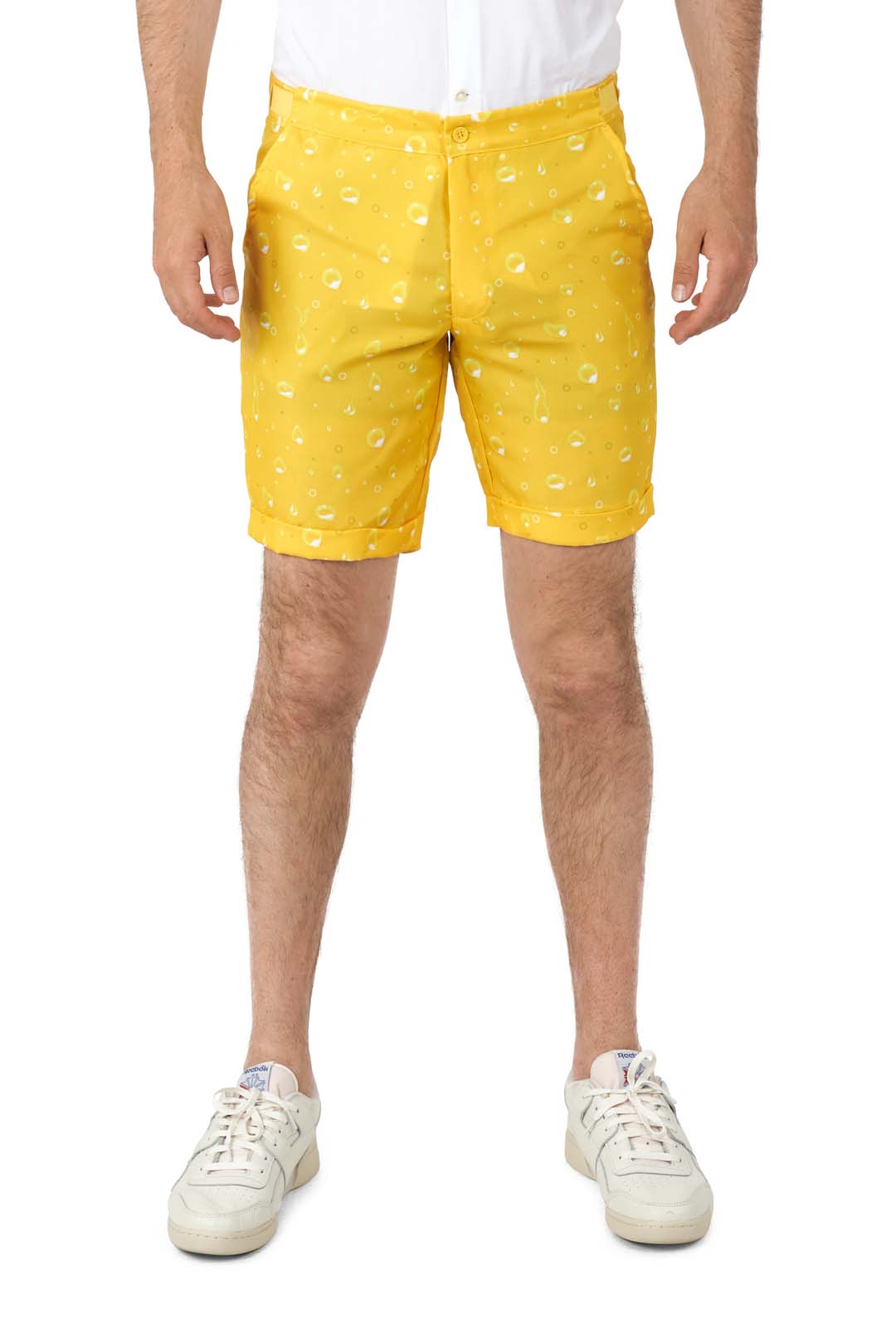 A person is wearing Suitmeisters Premium Beer Yellow shorts, featuring a water droplet pattern, paired with a tucked-in white shirt and white sneakers, posed against a white background.