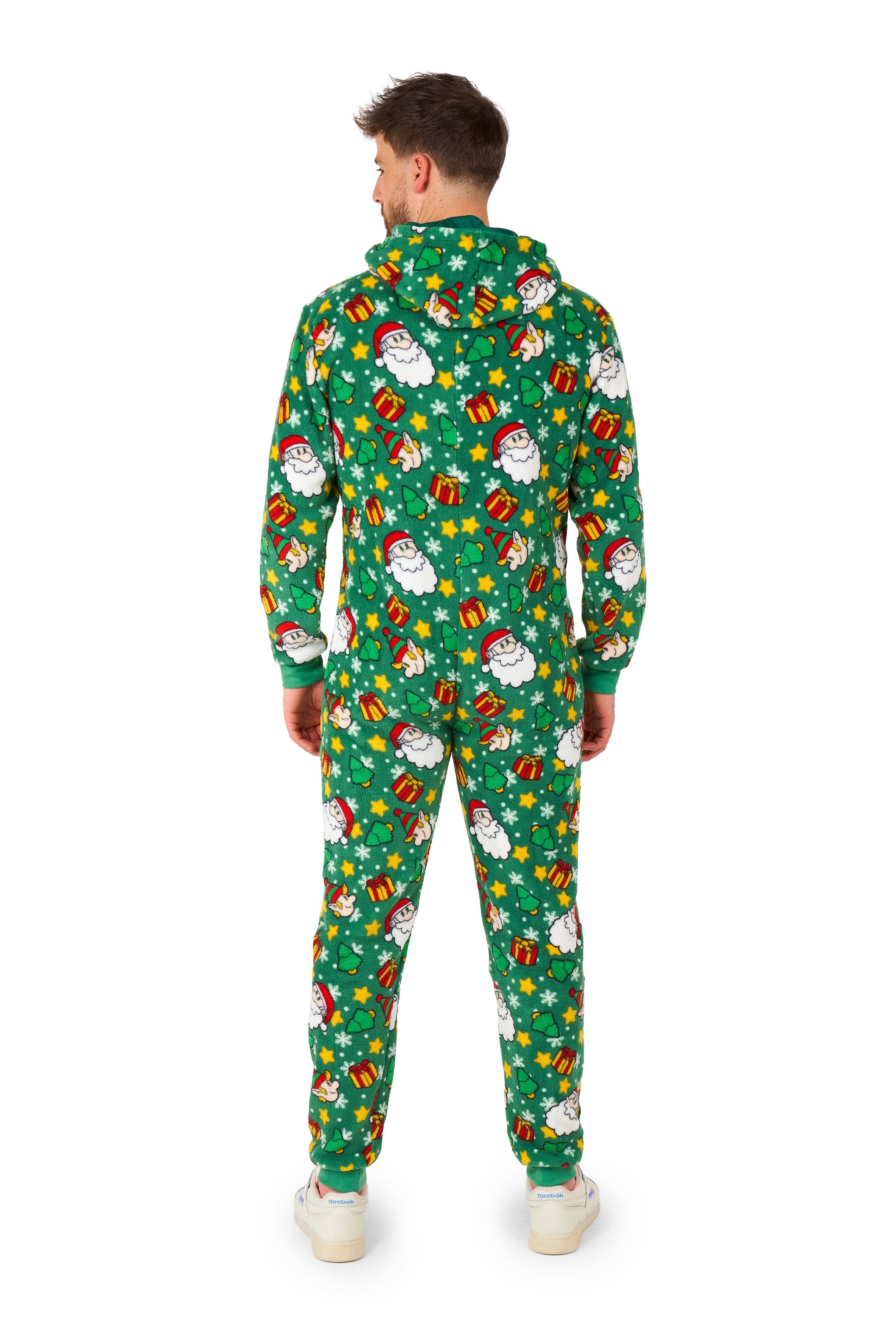 A person faces away, wearing the Suitmeister Santa Elves Green - Christmas onesie with festive holiday patterns like snowmen, presents, and snowflakes, paired with white shoes.