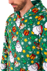 A man wearing the Suitmeister Santa Elves Green Christmas onesie, featuring festive patterns like Santa faces, Christmas trees, yellow stars, and gifts. Only his lower face and upper body are shown.