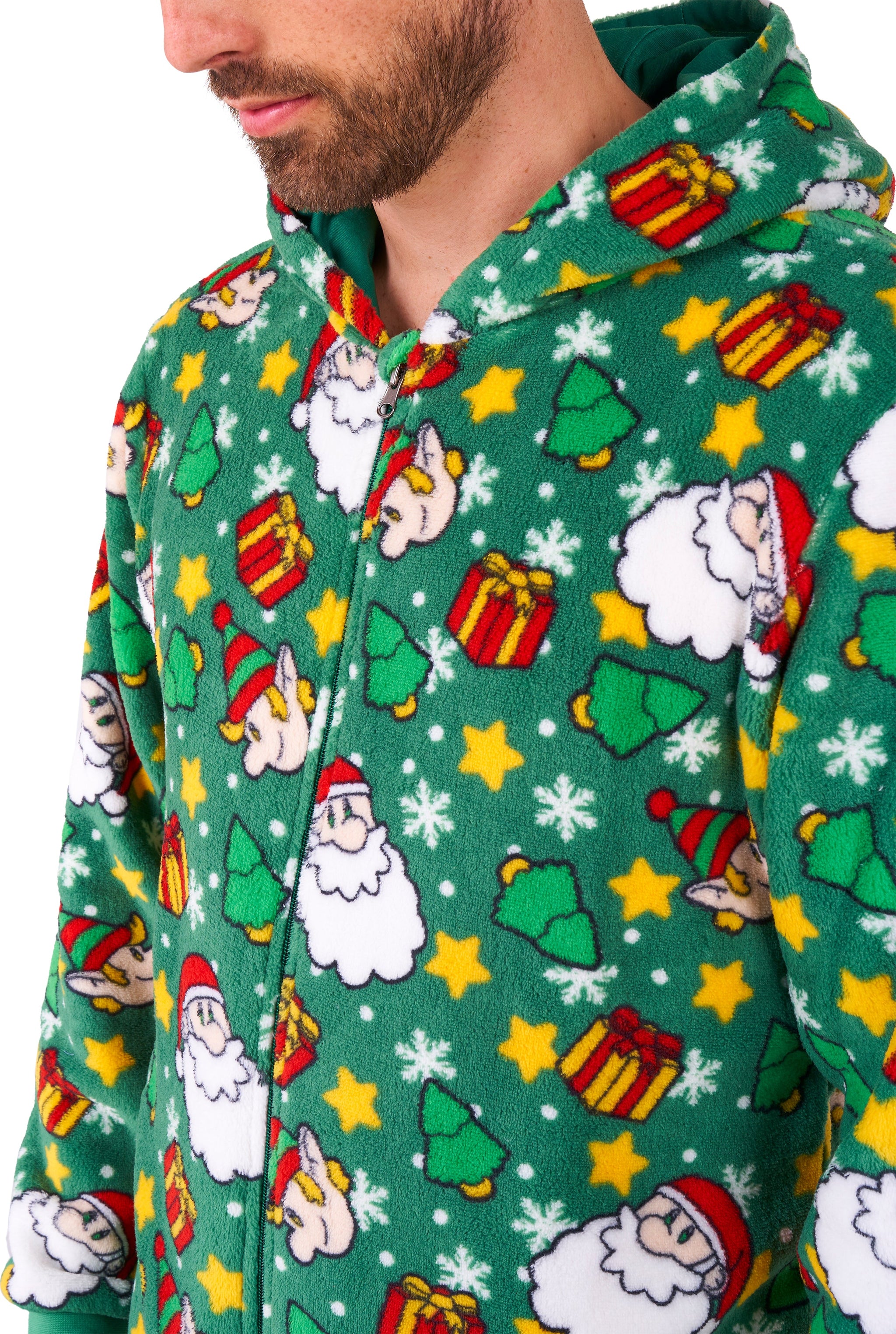 A man wearing the Suitmeister Santa Elves Green Christmas onesie, featuring festive patterns like Santa faces, Christmas trees, yellow stars, and gifts. Only his lower face and upper body are shown.