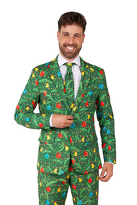 A man in the Suitmeister "Christmas Green Tree - Light Up" suit, featuring colorful ornaments and string lights pattern, with a white shirt and festive tie, stands against a white background.