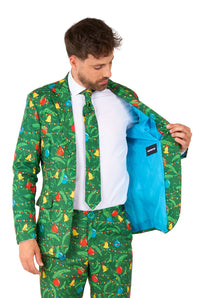 A man wears the Suitmeister Christmas Green Tree - Light Up suit featuring colorful Christmas ornament and light designs. He opens his jacket to reveal a bright blue lining, paired with a matching tie and a white shirt.