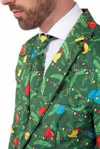 A man wears the Suitmeister Christmas Green Tree - Light Up suit, featuring Christmas tree branches, ornaments, and holiday lights. Only his lower face and upper body are visible; the look includes a matching festive tie.