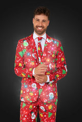 A smiling man wears the Suitmeister Christmas Red Icons - Light Up suit, featuring festive snowmen, trees, and gifts with a matching tie, set against a dark background.