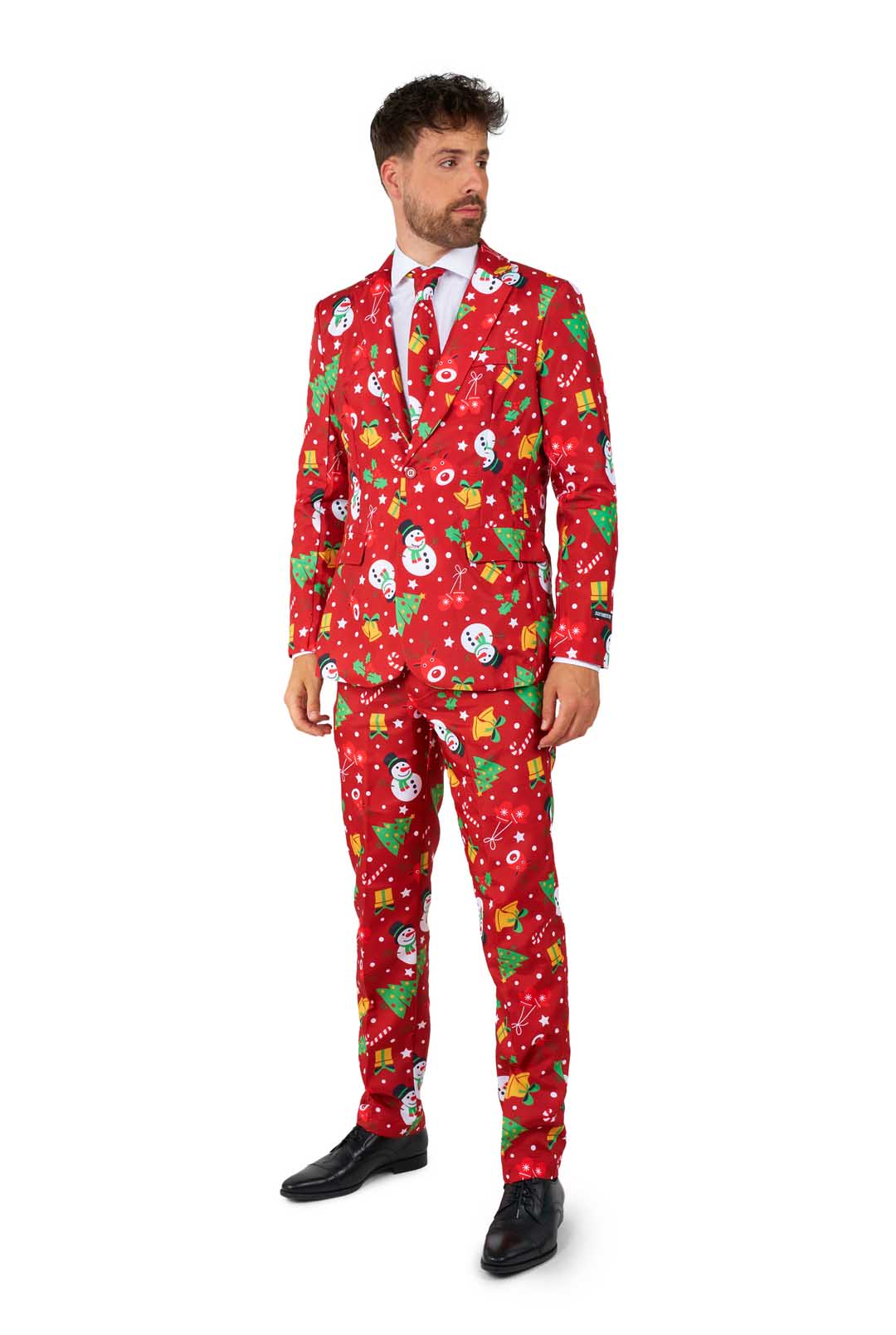 A man wears the Suitmeister Christmas Red Icons - Light Up suit, featuring festive patterns like snowmen, trees, and ornaments, paired with a white shirt and red tie. He looks to the side.