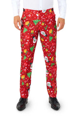 A person is wearing Suitmeister’s Christmas Red Icons - Light Up pants, featuring festive patterns of green trees, yellow gifts, white snowflakes, and snowmen, paired with a white shirt and black shoes.