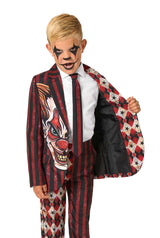 A child in a red and black clown-themed suit opening one side of the jacket to show the inner lining while wearing clown makeup.