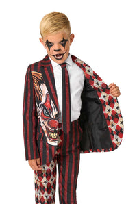 A child in a red and black clown-themed suit opening one side of the jacket to show the inner lining while wearing clown makeup.