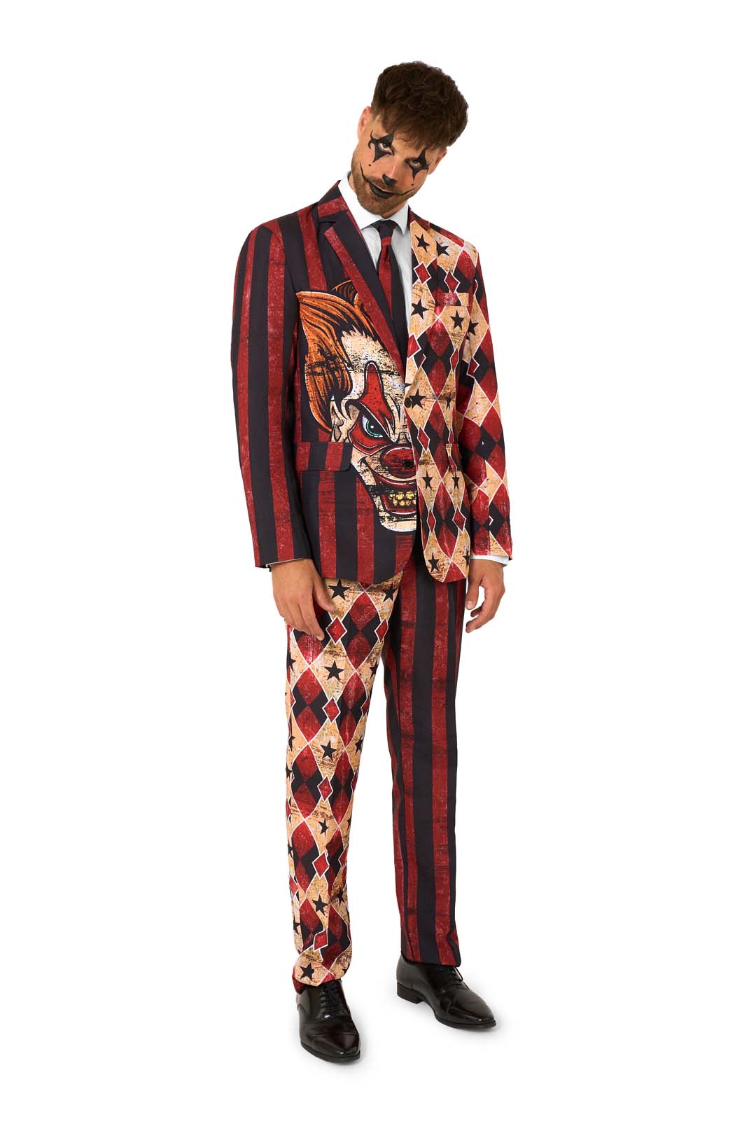 Full-body view of a child in a red and black patterned clown suit with a white shirt and black tie, standing with hands behind their back.