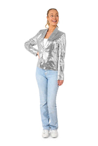 A smiling woman looks to the side, wearing the Suitmeister Sequins Silver sequin blazer with light blue jeans, a white top, and white sneakers, standing against a plain white background.