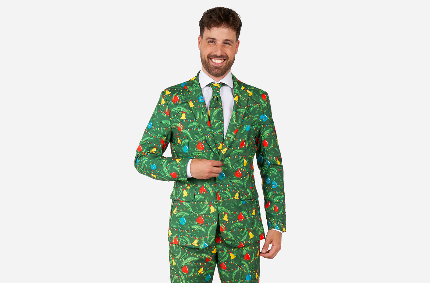 Image of a man wearing a green Christmas suit, standing in front of a white background, smilling at the camera. Suits consist of a blazer, pants and tie.